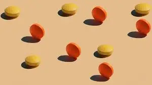 A collection of orange and yellow balls on a beige background, representing drugs used for treating erectile dysfunction.