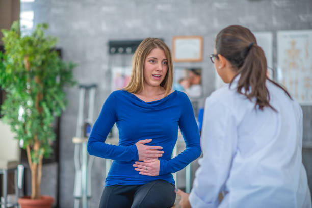 a lady with her handds on her belly standing along withna doctor